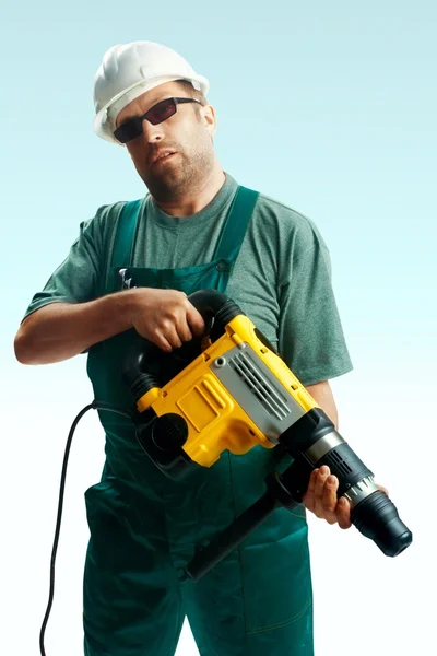 Müder Arbeiter mit Helm, schwarzer Brille und Overall hält Perforator in den Händen — Stockfoto