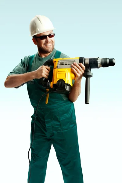 Log Workman i hjälm, svarta glasögon och overaller hålla perforator i sina händer och borrade över vit bakgrund — Stockfoto