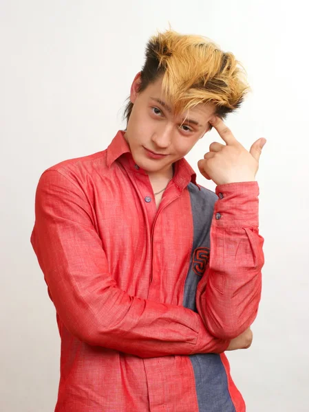 Thoughtful guy with golden hairstyle in the red shirt point his finger on his temple — Stock Photo, Image