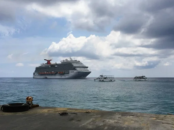 开曼群岛大开曼乔治敦港湾码头附近乌云蓝天下的嘉年华游轮形象 — 图库照片