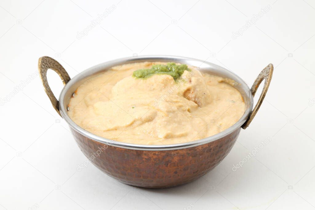 White gravy malai kofta in a copper brass bowl on white background