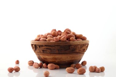 Beyaz arka planda tahta bir kasede çiğ fıstık ya da Arachis.