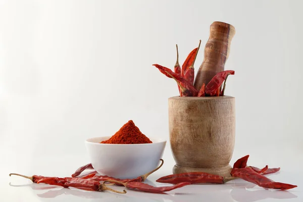 Red chillies with red chilly powder on white background.