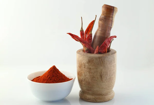 Red chillies with red chilly powder on white background.