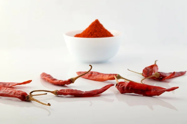 Red chillies with red chilly powder on white background.