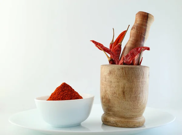 Red chillies with red chilly powder on white background.