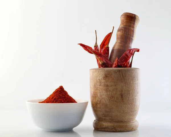 Red chillies with red chilly powder on white background.