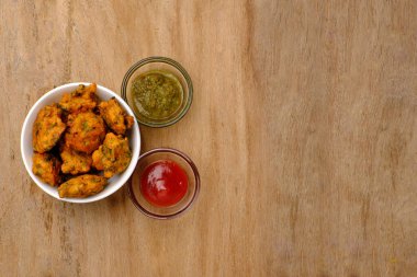 Pakora domates soslu Hint atıştırması ya da ahşap arka planda fotokopi alanı olan turşu.