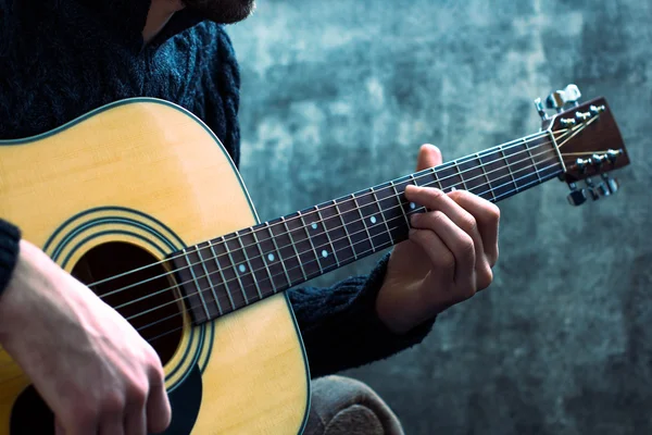 genç adam bir beton duvar arka üzerinde bir akustik gitar çalmaya