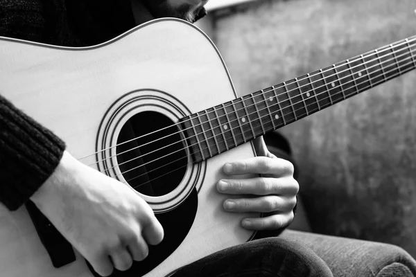 genç adam bir beton duvar arka üzerinde bir akustik gitar çalmaya