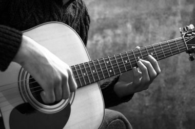 genç adam bir beton duvar arka üzerinde bir akustik gitar çalmaya