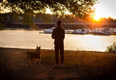 köpekli iskelede gün batımını izlemek adama