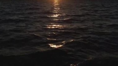 Hava aracı atışı. Denizin üzerinde şafak. Soluk sarı güneş. Sakin hava.