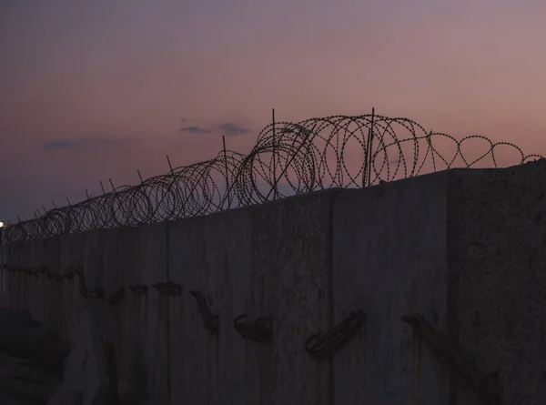 Mur de prison en fil barbelé. Coucher de soleil. panorama. — Photo