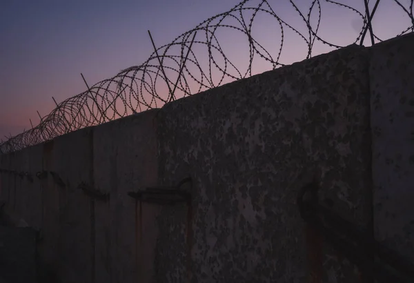 Mur de prison en fil barbelé. Coucher de soleil. panorama. — Photo