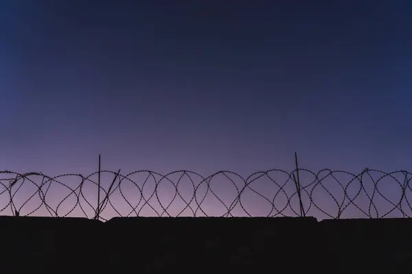 Mur de prison en fil barbelé. Coucher de soleil. panorama. magenta ciel — Photo