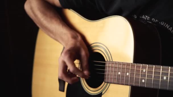 音楽家はアコースティックギターを演奏する。暗い背景 — ストック動画