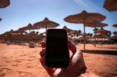 Plajda elinde engelli bir akıllı telefon var. İnsanlardan uzak dur. yakın plan