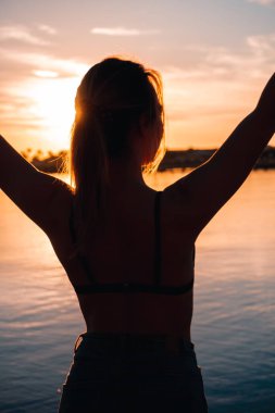 Genç ve güzel bir kız deniz kıyısında ısınıyor. şafak.