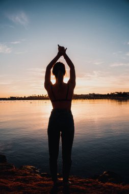 Genç ve güzel bir kız deniz kıyısında ısınıyor. şafak.