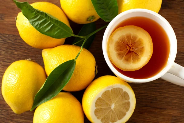 Lemonade in a white cup. Lemon fruits with lemonade on wooden background. close-up. — Stock Photo, Image