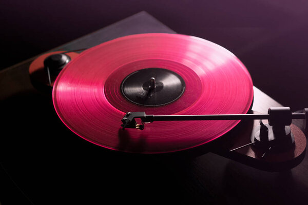 Vinyl DJ turntable in club lighting. close-up. pink tint. retro style