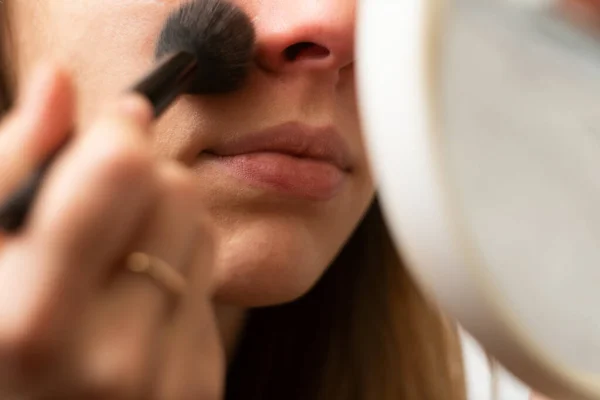 Girl makes herself makeup. close-up. makeup mirror.