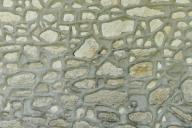 Çimento eklemli doğal bir taştan yapılmış eski bir duvar.