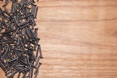 Ahşap arka planda siyah çelik çiviler, rastgele sola saçılmış, reklam ya da reklam için boşluk bırakıyor.