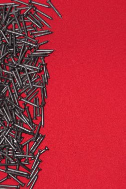Kırmızı arka planda siyah çelik çiviler, rastgele sola saçılmış, reklam için boşluk bırakılmış.