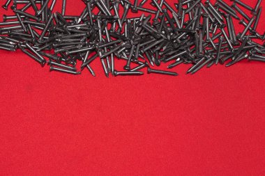 Kırmızı arka planda siyah çelik çiviler. Rastgele üst tarafa saçılmış. Reklam için yer var..