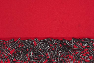 Kırmızı arka planda siyah çelik çiviler, rastgele dağılmış.