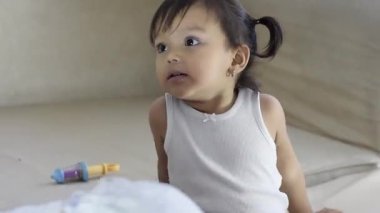 Latin kız kanepeye yaslanmış, başını arkaya yaslamış, evde dinleniyor ve başka bir kızla oynuyor..