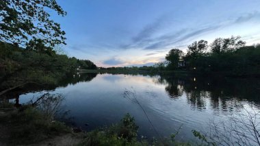 Gün batımında ağaçlarla birlikte göl ve gökyüzü.