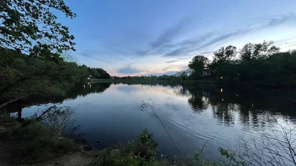 Gün batımında ağaçlarla birlikte göl ve gökyüzü.