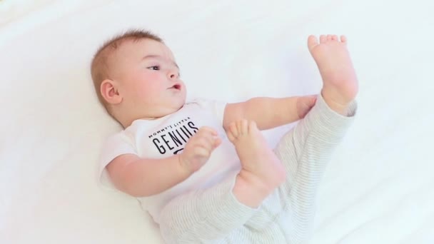 Kis baby boy játék a lábát, fehér háttér — Stock videók