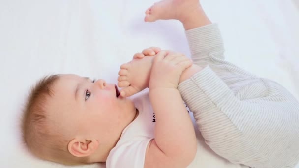 Little boy playing with his foot and trying to bite her — Stock Video