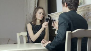 Çift oturma önünde birbirlerine sevgi dolu, kırmızı şarap ile gözlük tıklatması.