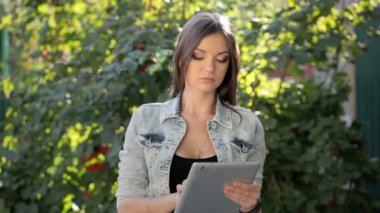 Güzel esmer kız yaz parkta tablet hoşlanır.