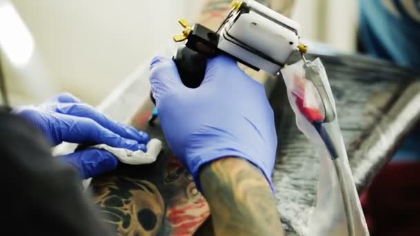 Tattoo ink rubs his hand on the client — Stock Video