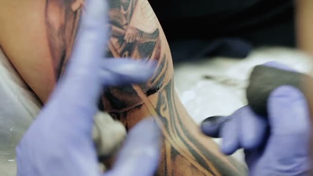Professzionális tetováló mester felhívja a férfi vállát.