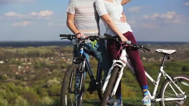 Hombre y mujer con bicicletas en una colina observando el atardecer . — Vídeos de Stock