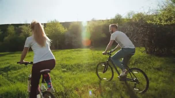 Man och kvinna ridning cyklar på den gröna ängen. — Stockvideo