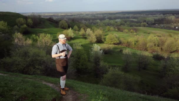 Birraio con birra scura su uno sfondo di verdi colline . — Video Stock