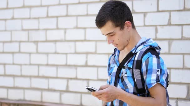 O jovem está digitando uma mensagem em um smartphone . — Vídeo de Stock