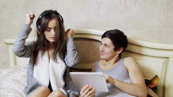Fiatal pár, hallgathatja a zenét a fejhallgatót, és használja a tabletta. — Stock videók