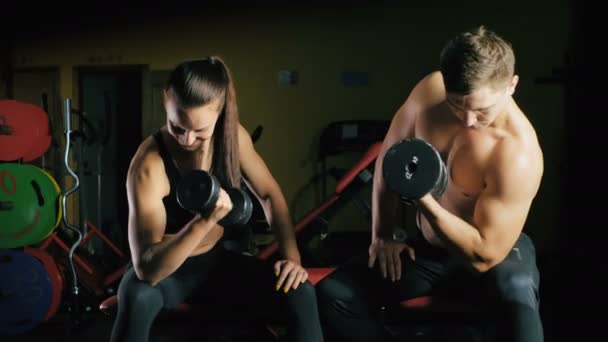 Hombre y mujer trabajando sus brazos en el gimnasio . — Vídeos de Stock