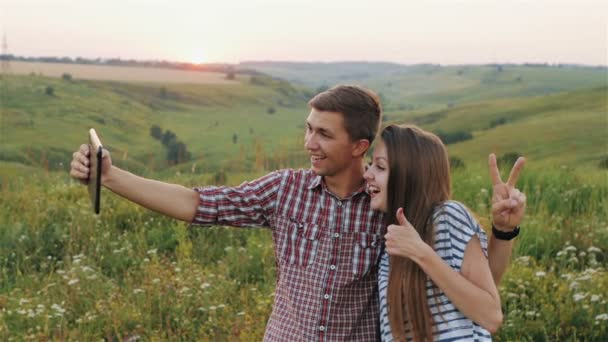 Aantrekkelijke jonge meisje en de jongen nemen Selfie bij zonsondergang. Slow Motion — Stockvideo