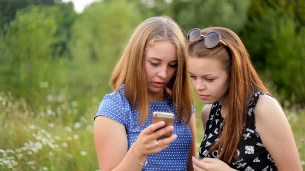 Dos chicas navegan por Internet en su teléfono . — Vídeos de Stock