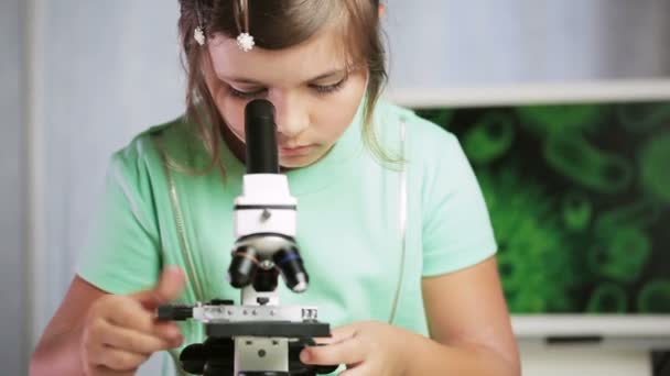 Молодая девушка-ученый смотрит в микроскоп — стоковое видео